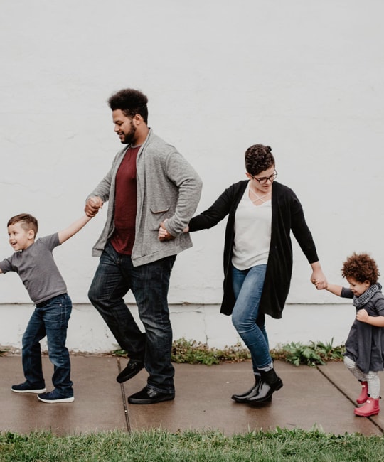 A happy family walking on sidewalk.